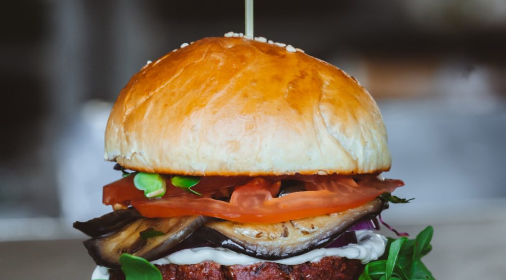 Ein Burger belegt mit Gemüse und einem Patty.